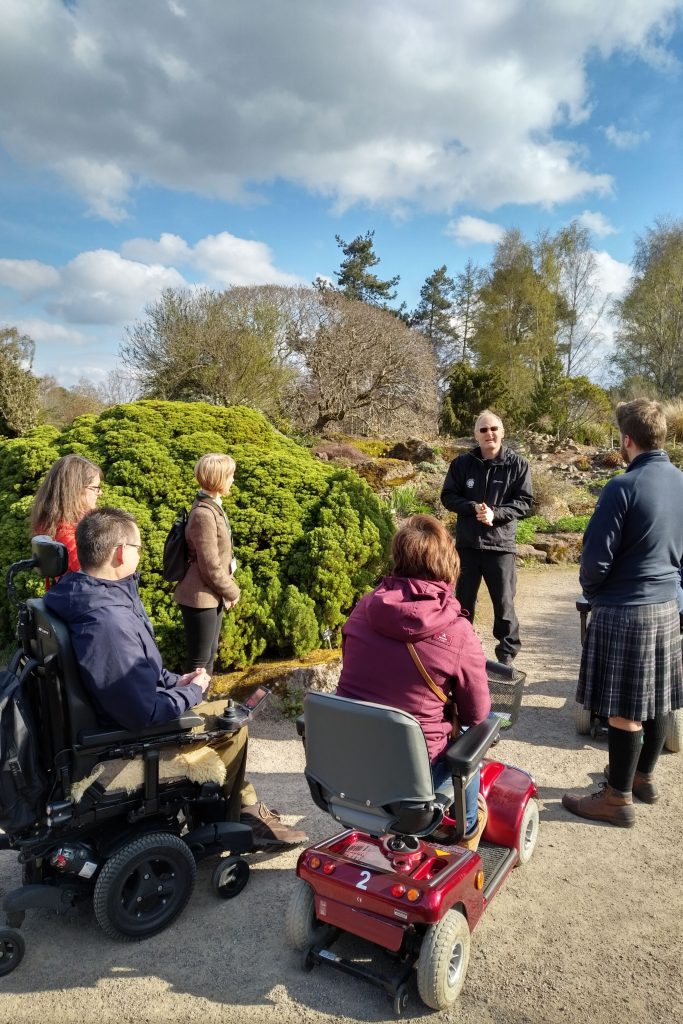 Guiding group in wheelchairs through botanic gardens in Edinburgh